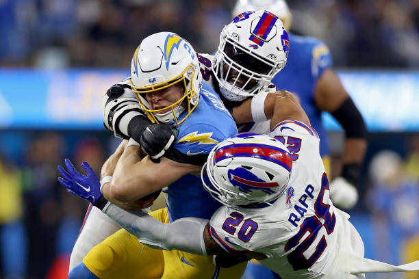Easton Stick #2 of the Los Angeles Chargers runs with the ball while being tackled by Linval Joseph #93 and Taylor Rapp #20 of the Buffalo Bills